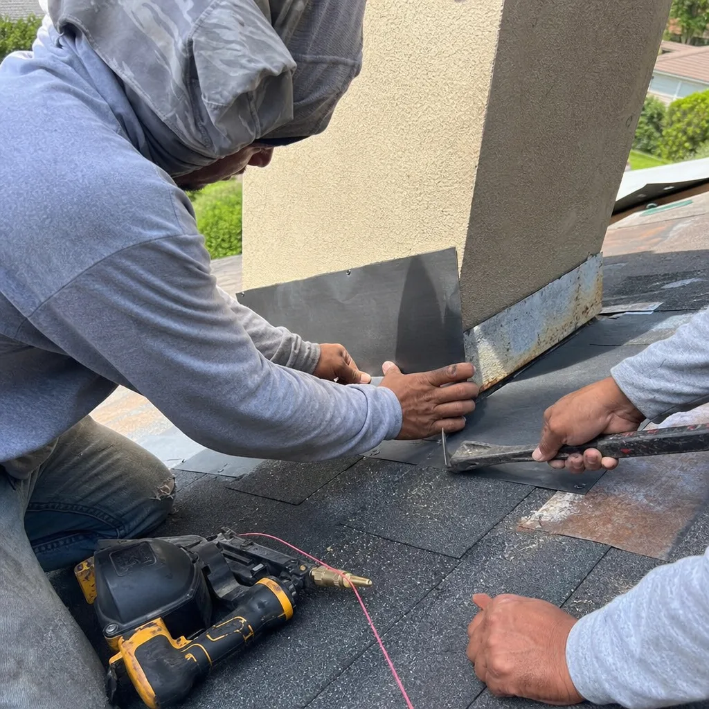Professional roofers installing chimney flashing on a residential roof